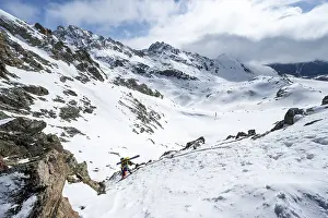 Mountaineer with skis climbing up a steep snow slope to the fork Porta d'Es-cha
