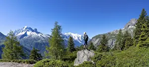Mountaineer standing on rocks, mountain panorama with glaciated mountain peaks