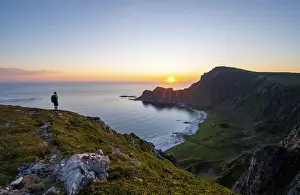Mountaineer in front of view of coastal landscape at sunset