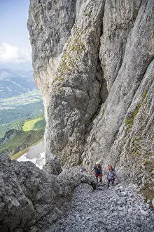 Two mountaineers with helmets climbing on a rock face