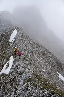 Two mountaineers with helmets in the mountains in fog