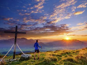 Mountaineers at the Schlenken summit cross at sunset clouds (cumulus)
