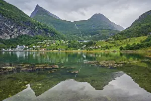 Mountainous landscape with a calm fjord reflecting the surrounding mountains and village
