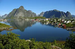 Mountains and houses reflect in the fjord Reine Moskenesoya Lofoten Norway