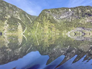 Mountains with reflections in the water against a blue sky in Doubtful Sound