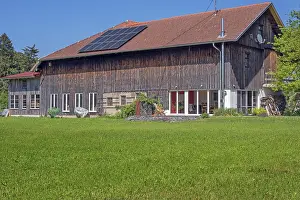 Mown spring meadow, barn converted into a residential building with solar panel near Ried