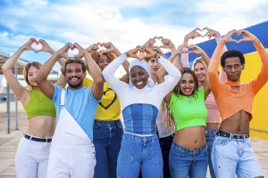 Multi-ethnic young people standing gesturing heart shape with hands outdoors in a urban space