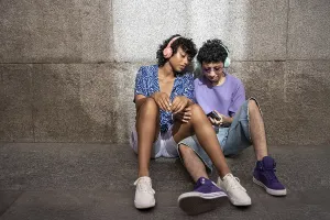 A multiethnic LGBTQ+ couple sitting against a stone wall