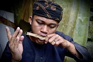A musician concentrates on playing a traditional bamboo instrument