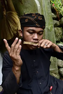 A musician concentrates on playing a traditional bamboo instrument