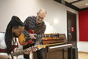 Two musicians play electric guitars in a vibrant recording studio