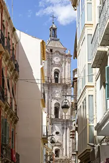 Narrow alley with a view of an old church tower under a clear sky