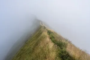 Narrow ridge, steep grassy mountains in the mist