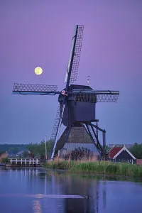 Netherlands rural landscape with windmills at famous tourist site Kinderdijk in Holland in twilight with full moon