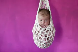 Newborn baby, five days, suspended in a "stork's bag"<br> Newborn baby