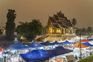 Night market and the Haw Pha Bang temple of the Royal Palace in Luang Prabang at dusk