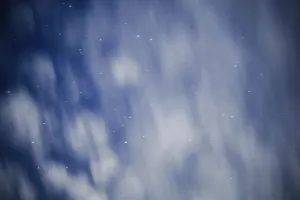 A night sky with blurred clouds and scattered stars creating an ethereal atmosphere