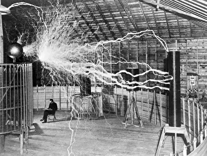 Nikola Tesla sits next to his amplifier transmitter
