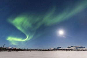 Northern Lights (Aurora Borealis) at full moon over snow-covered mountains