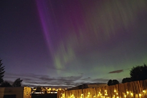 Category Scandinavia Prints: Northern Lights in the night sky above an illuminated fence and a campsite