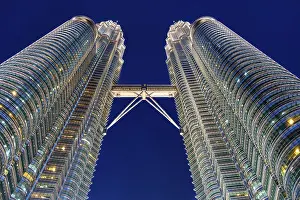 Nov 20, 2019 - Kuala Lumpur, Malaysia: Symmetry of Petronas Twin Towers with connecting skybridge glowing in night sky
