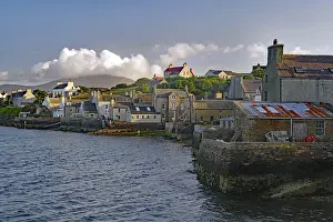 Numerous buildings at a stone harbour under a cloudy sky