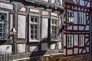 Oblique view of half-timbered houses with street lanterns with sunlight falling at an angle