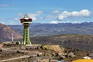 Observation tower on a hill with a cross and clouds in the blue sky in the background
