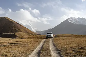 Off-road vehicle on a track between yellow meadows