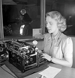 Office girl in the 1940s. A woman is sitting at a office desk typing on her typewrite