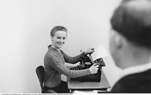 Office worker in the 1950s. She sits at a typewriter in an office