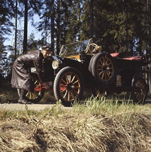 The old car. A man in a typical old fashioned driver's outfit complete with a leather cap