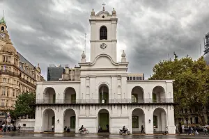 An old colonial style building with clock tower under a cloudy sky in the city