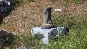 An old column on a pedestal surrounded by grass at a historical site