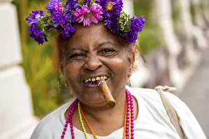 Old Cuban woman with flowers and cigar posing for a tip for tourists