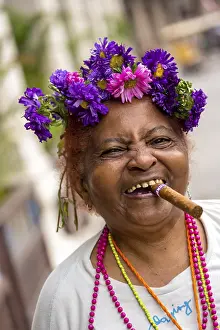 Old Cuban woman with flowers and cigar posing for a tip for tourists