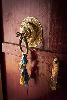 Old door at Buddhist monastery temple decorated with ancient doorknob and tassel