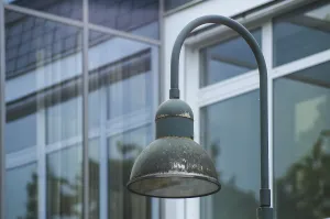 Old green streetlamp stands in front of modern glass building