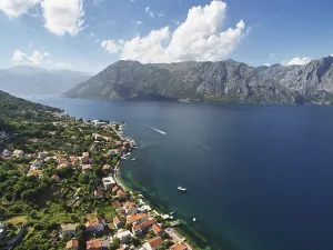 Old houses with red roofs on the shore of the Bay of Kotor at the foot of the mountains