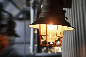 Old lantern with a special protective grille and a glass canopy shines yellow