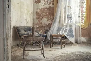 Old room with rattan furniture and translucent curtains in front of peeling walls