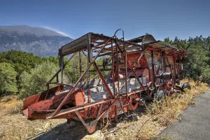 Old, rusty combine harvester in mountainous landscape with clear sky