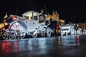 The old square of the night krakow with luminous horse-drawn carriages