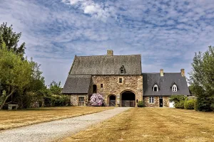 An old stone house with a gravelled path and a blue sky