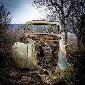 Old truck carcass rusty and boned amidst fields in winter
