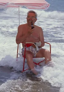 Older man with solar chair and sunshade by the sea