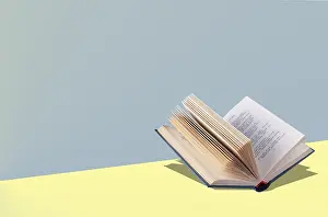 An open book lies on a yellow table