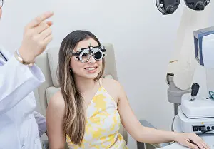 Framed Print : Optometry eye health concept. Optometrist assisting patient with optometrist trial frame