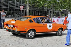 Orange Audi classic car on an urban street at an event