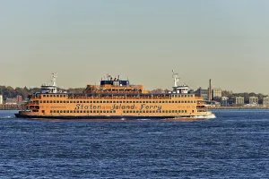 Orange-coloured Staten Island Ferry on water against a city backdrop